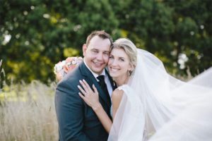 Testimonials | Vinka Design | Real Bridal Reviews from Our Clients | Angela and Tony smiling embracing with bespoke veil in the breeze