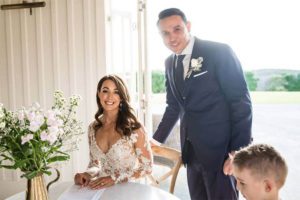 Testimonials | Vinka Design | Real Bridal Reviews from Our Clients | Haley and Mike signing wedding register with Hayleys gorgeous bespoke gown lace top detailing highlighted