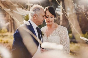 Testimonials | Vinka Design | Real Bridal Reviews from Our Clients | Jade and Brett embrace with lace detail of bespoke gown highlighted