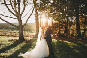 Testimonials | Vinka Design | Real Bridal Reviews from Our Clients | Louise and Ryan in dappled sunlight in a field with bespoke gown highlighted