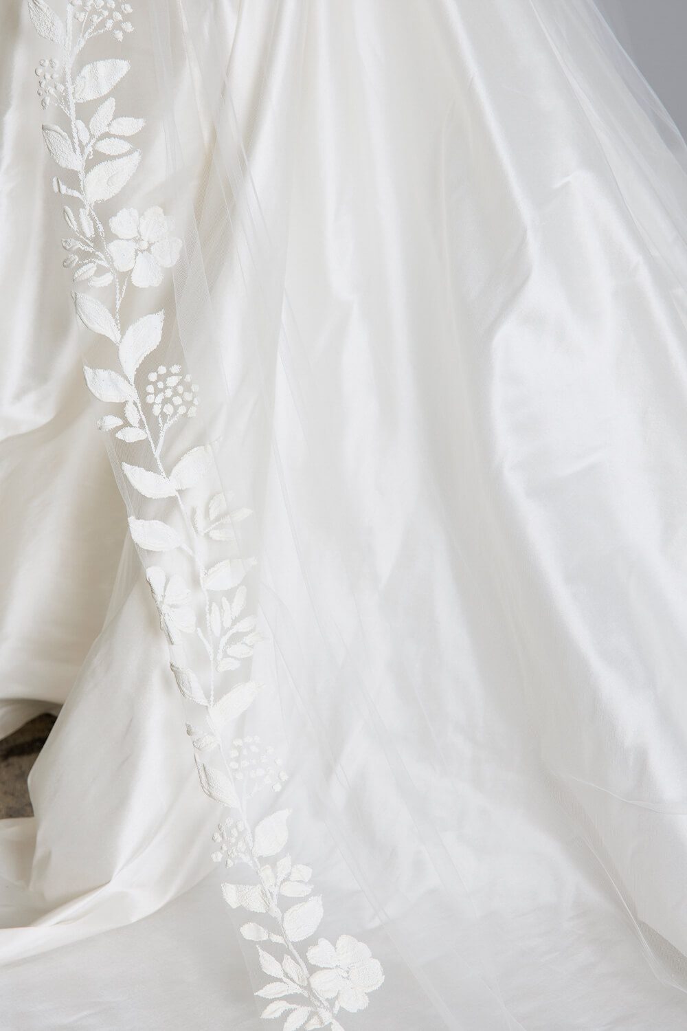Fleur hand-painted bridal veil by Vinka Design, featuring delicate white floral motifs along the edge of a sheer tulle veil, styled with an ivory wedding gown.