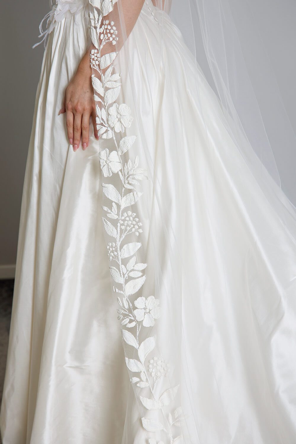Fleur hand-painted bridal veil by Vinka Design, featuring delicate white floral motifs along the edge of a sheer tulle veil, styled with an ivory wedding gown.