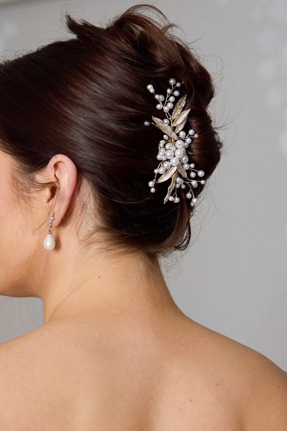 Imogen soft gold bridal headpiece by Vinka Design, featuring delicate gold metal leaves and clusters of luminous pearls, styled in a bridal updo.