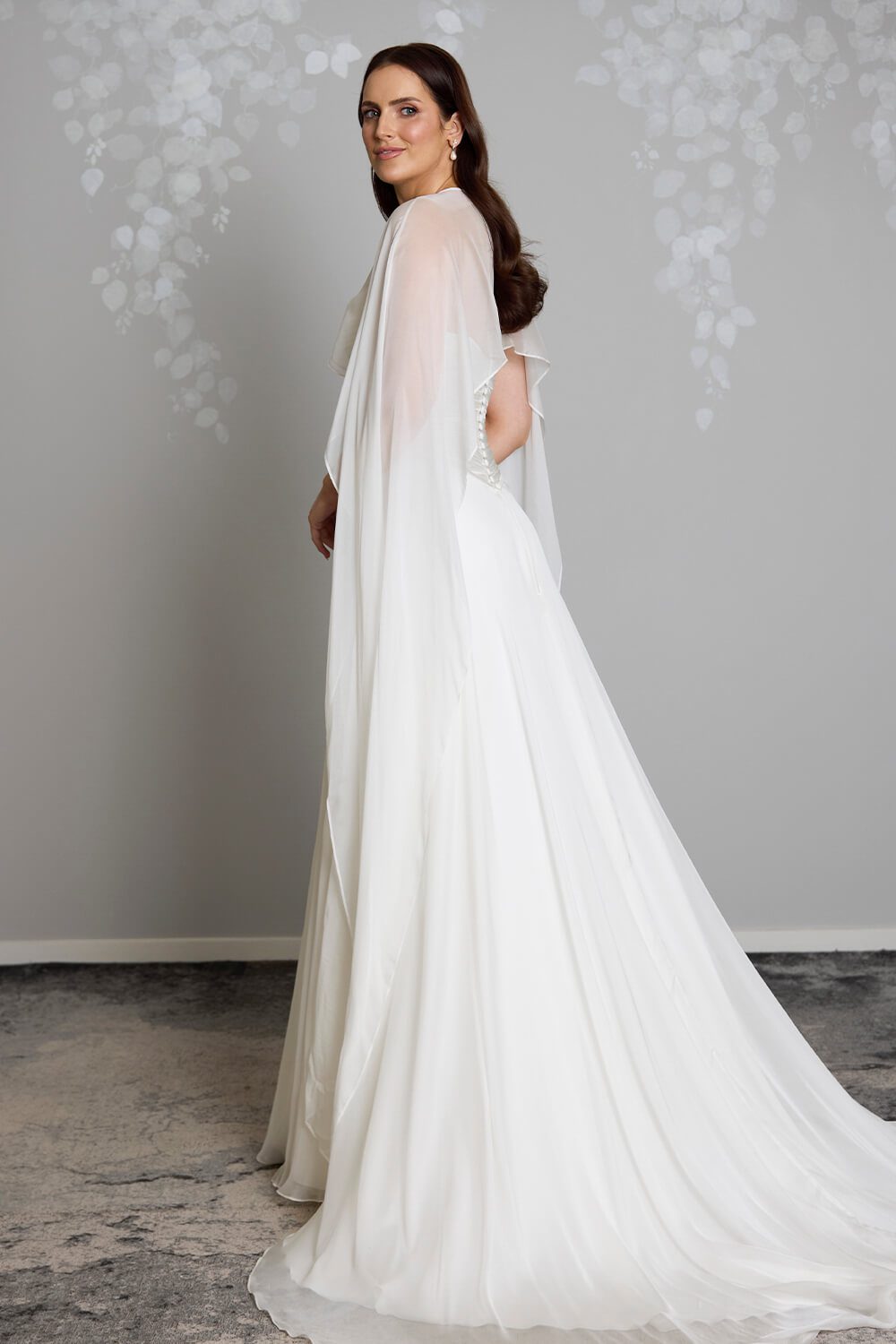 Jade silk chiffon bridal mantle by Vinka Design, featuring delicate pearl buttons at the shoulder and flowing sheer panels, pictured with the Jade and Reem wedding gowns.