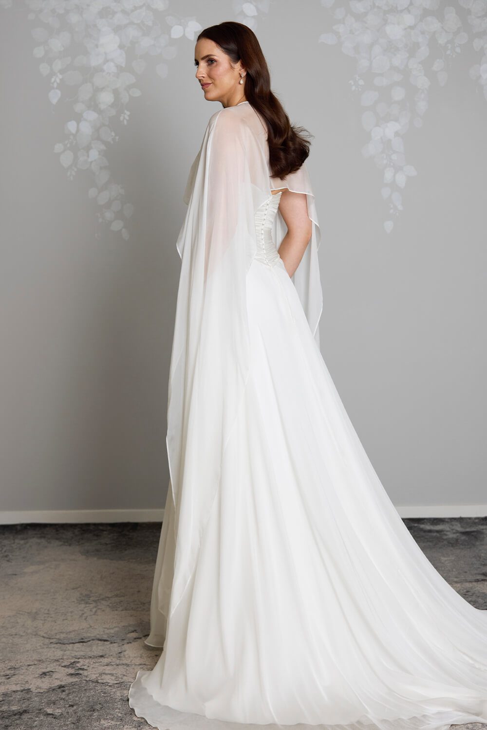 Jade silk chiffon bridal mantle by Vinka Design, featuring delicate pearl buttons at the shoulder and flowing sheer panels, pictured with the Jade and Reem wedding gowns.