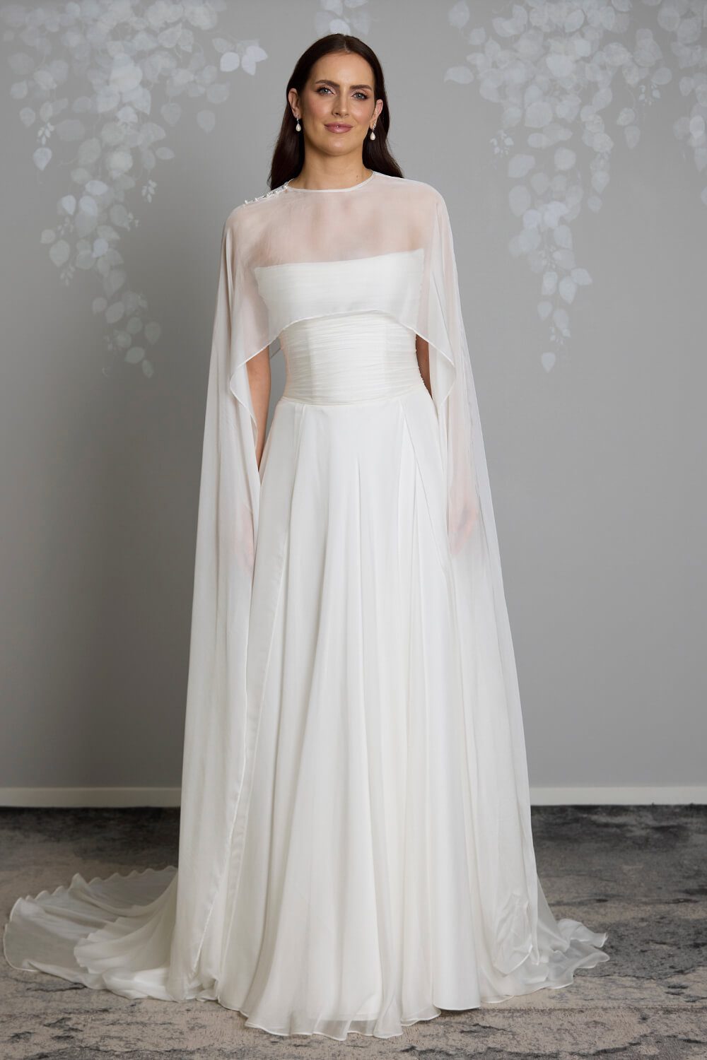 Jade silk chiffon bridal mantle by Vinka Design, featuring delicate pearl buttons at the shoulder and flowing sheer panels, pictured with the Jade and Reem wedding gowns.