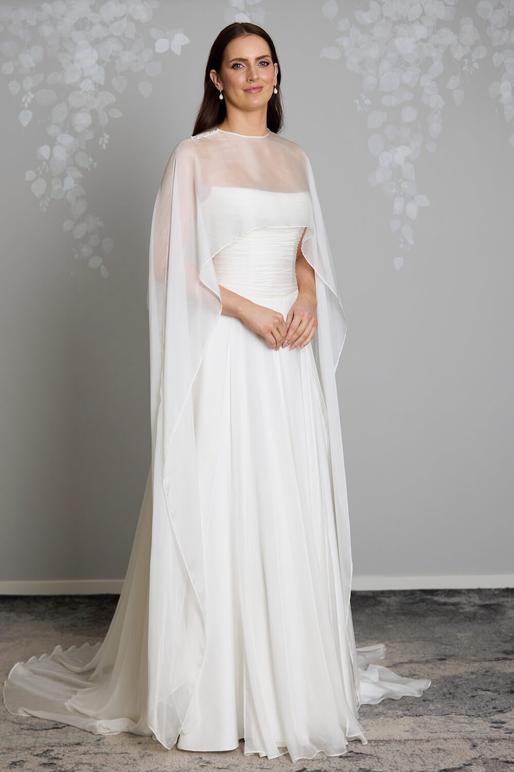 Jade silk chiffon bridal mantle by Vinka Design, featuring delicate pearl buttons at the shoulder and flowing sheer panels, pictured with the Jade and Reem wedding gowns.