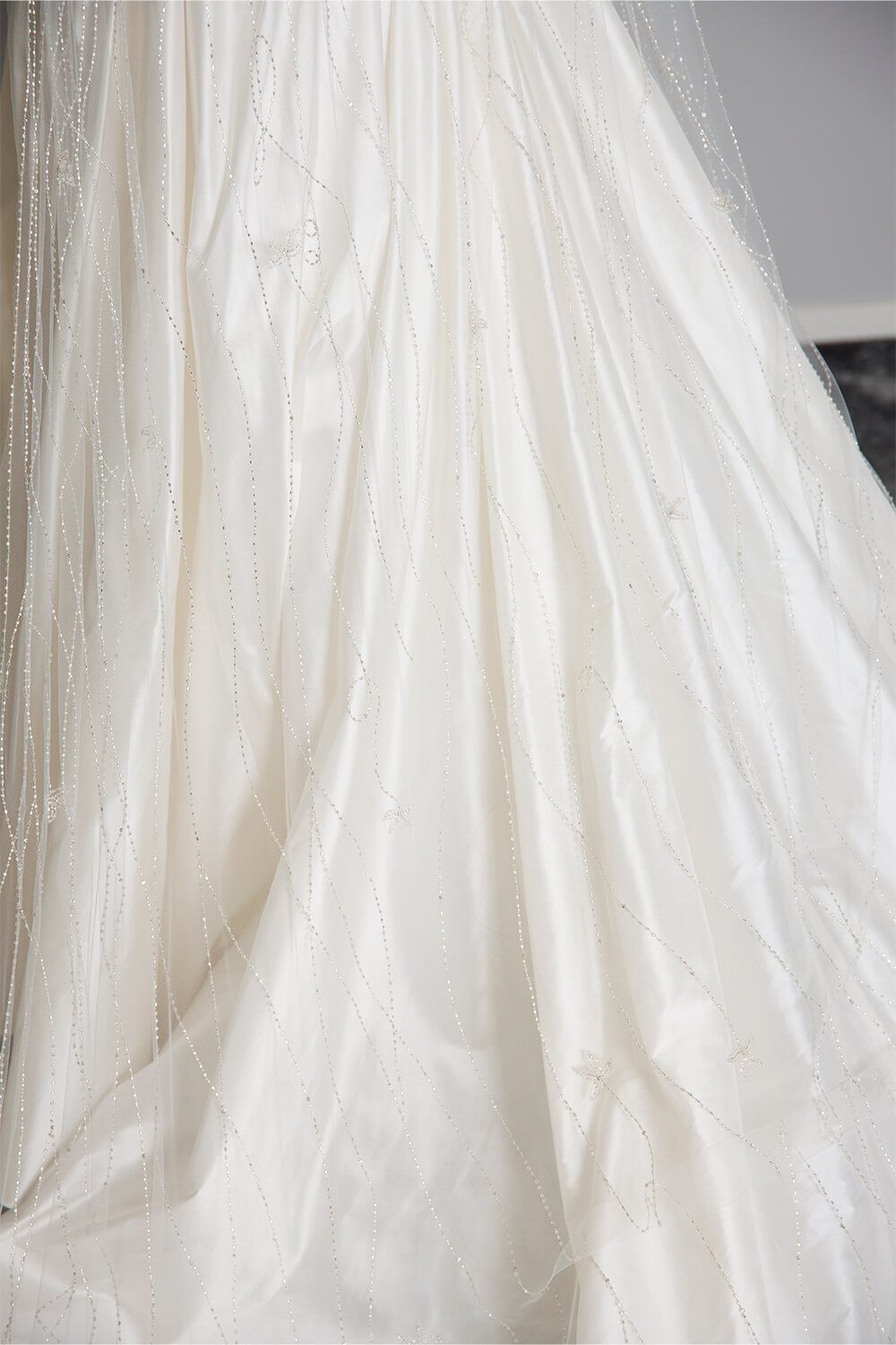 Ivory Krystal bridal veil featuring hand-beaded vine detailing in ivory thread, highlighted with Swarovski diamantes, draped over a white satin wedding gown.