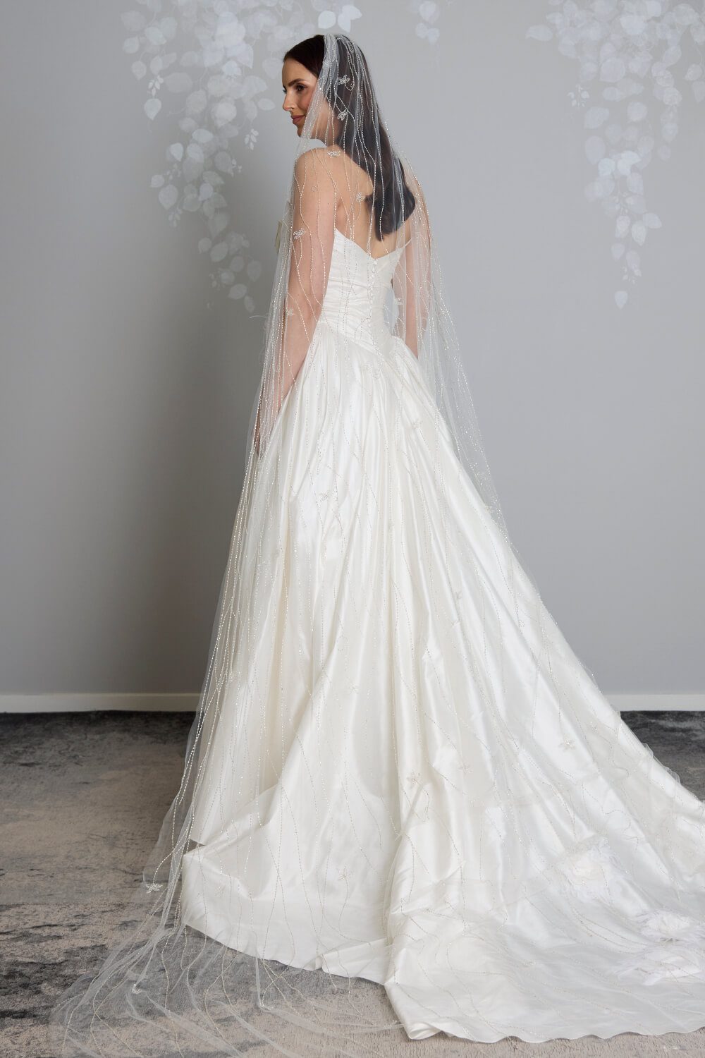 Ivory Krystal bridal veil featuring hand-beaded vine detailing in ivory thread, highlighted with Swarovski diamantes, draped over a white satin wedding gown.