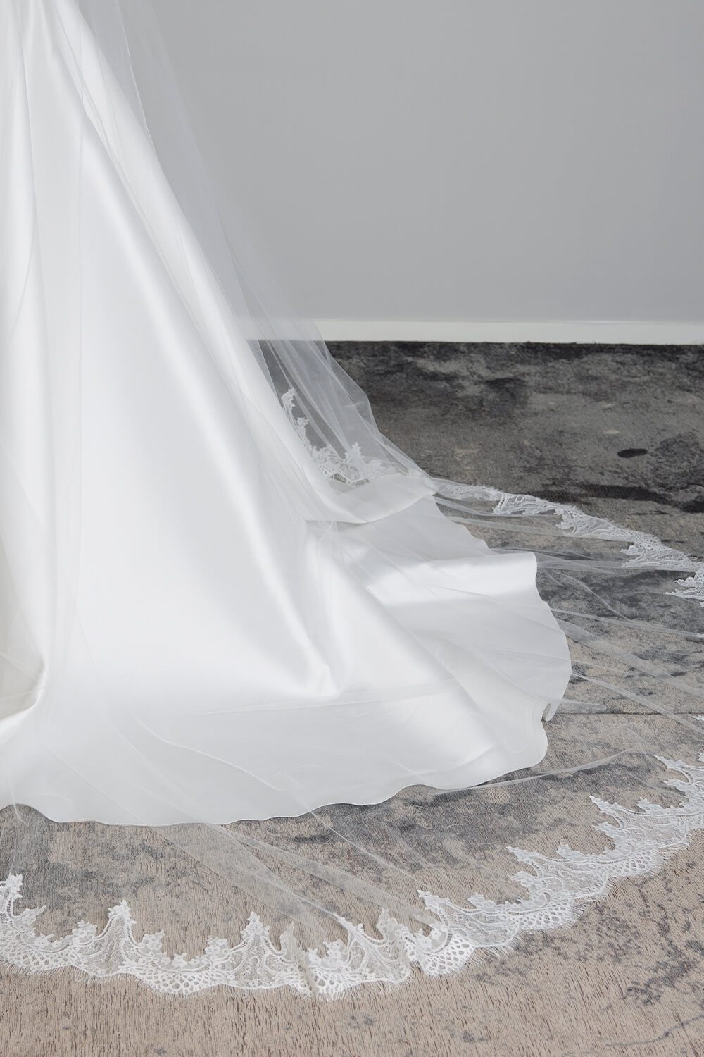 Bride wearing the Quinn two-tier ivory tulle wedding veil, featuring an intricate Chantilly lace edge and an 80cm blusher, styled with a satin wedding gown.