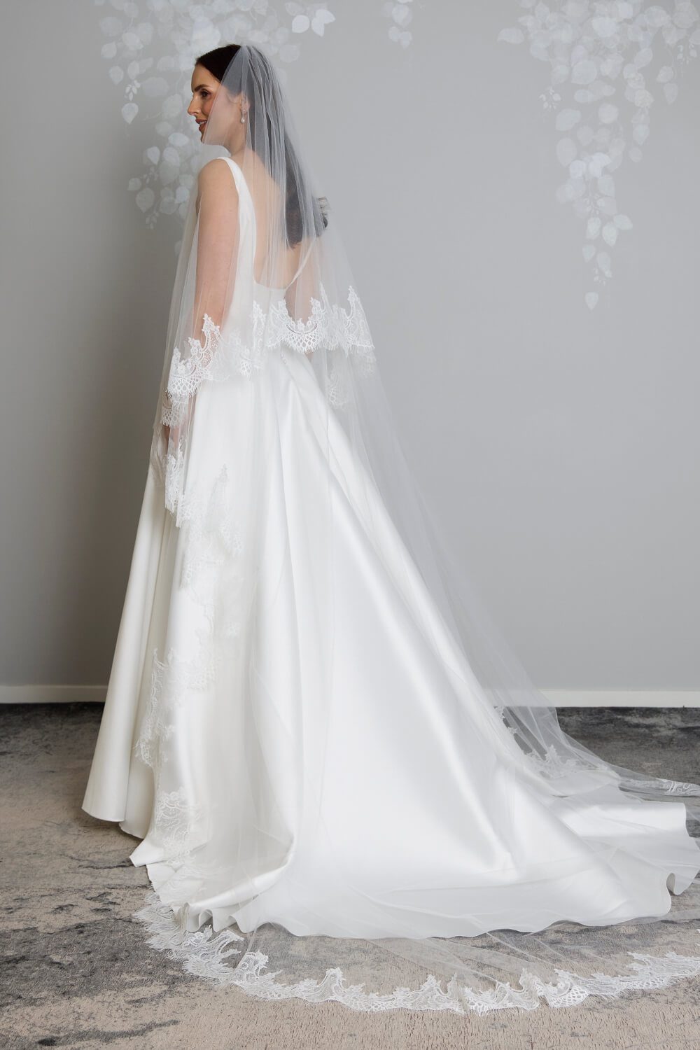 Bride wearing the Quinn two-tier ivory tulle wedding veil, featuring an intricate Chantilly lace edge and an 80cm blusher, styled with a satin wedding gown.