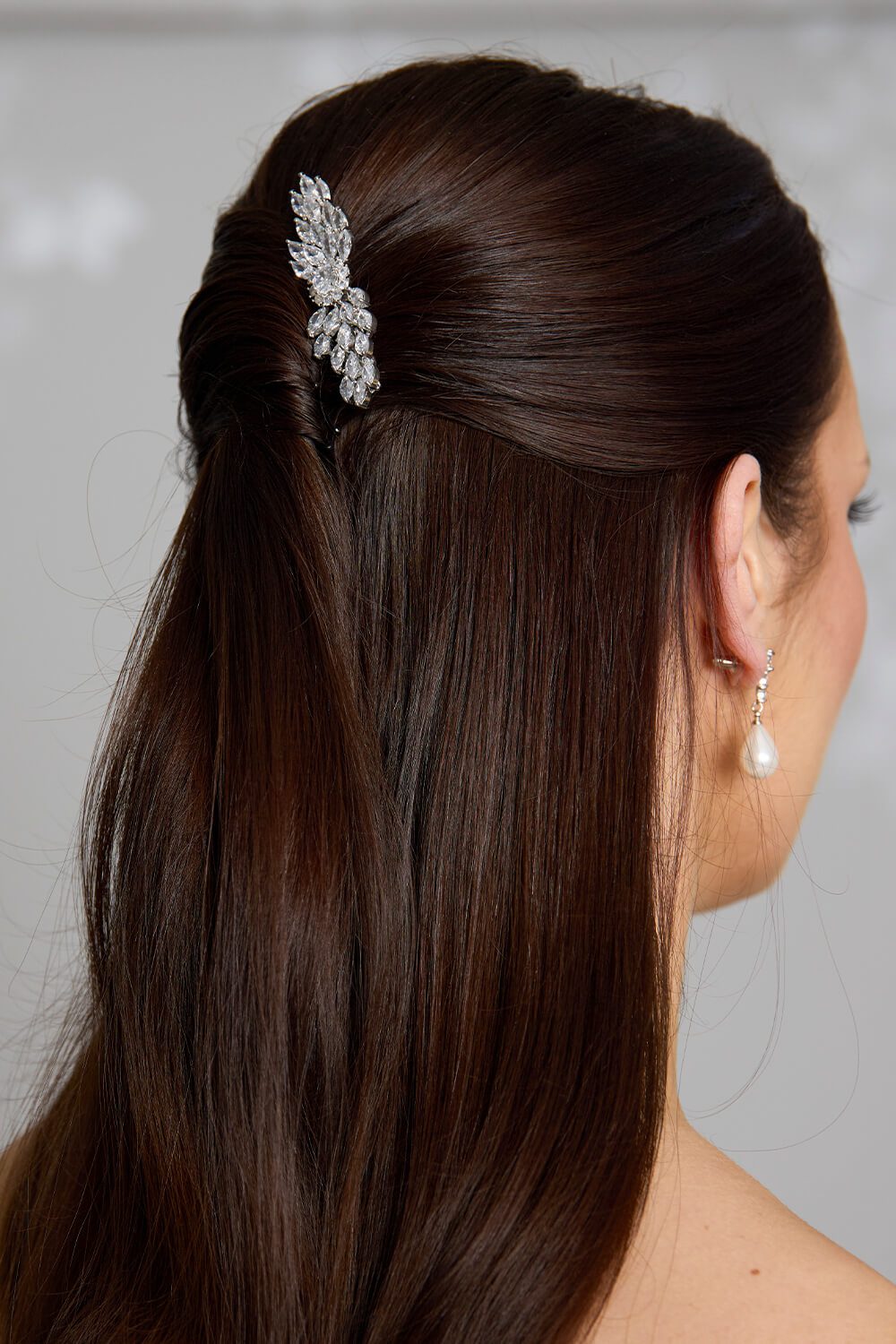 Close-up of the Sylvie crystal bridal comb featuring marquise-cut crystals in a leaf-inspired design, styled in a brunette model’s half-up hairstyle.