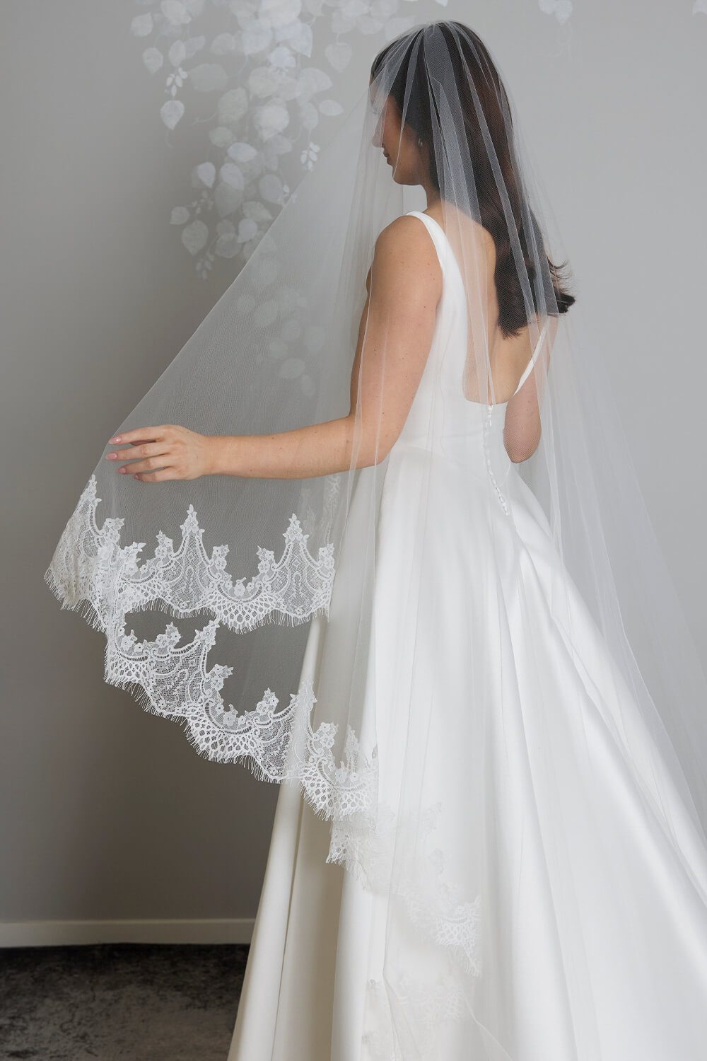 Bride wearing the Quinn two-tier ivory tulle wedding veil, featuring an intricate Chantilly lace edge and an 80cm blusher, styled with a satin wedding gown.
